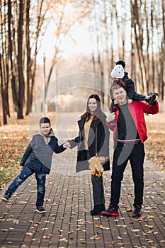 Caucasian family goes for a walk in the autumn park with two children