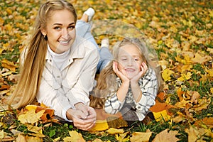The Caucasian family has fun in the park. Girl and mother lie on a blanket, a young woman looks at the camera and smiles