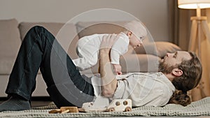 Caucasian family at home adult bearded father dad lying on floor with little daughter son baby playing with child