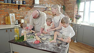 Caucasian family kneading dough, father showing tomato to son, family concept.