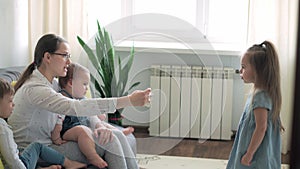 caucasian family little children girl boy and mom talking in video conference by smartphone together in living room at