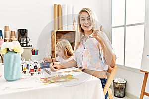 Caucasian family of mother and daughter painting at art studio smiling happy and positive, thumb up doing excellent and approval