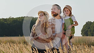 Caucasian family mother father woman and man with little daughter child girl in heat standing in wheat field outdoors