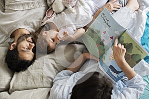 Caucasian family reading fairy tales to they daughter with happiness
