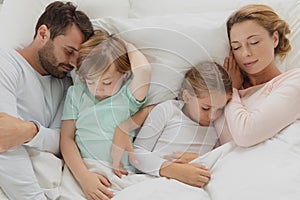 Caucasian family sleeping together in bed