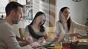 Caucasian family of three sharing breakfast food together.