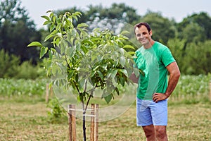 Caucasian farmer by a young walnut tree