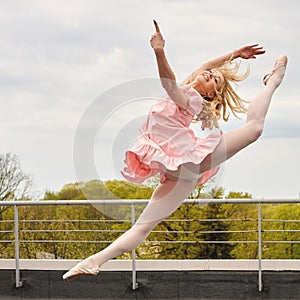 Caucasian fashion ballerina leaping on the roof