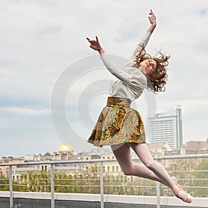 Caucasian fashion ballerina leaping on the roof