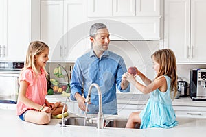 Caucasian father dad gives children daughters fresh fruits to eat