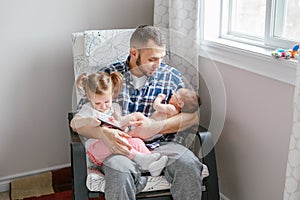 Caucasian father dad sitting with toddler daughter and newborn infant son watching cartoons on smartphone.