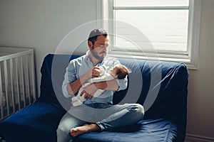 Caucasian father feeding newborn baby son daughter with milk