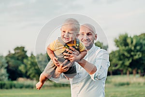 Caucasian father hugging playing with toddler baby boy. Parent holding carrying lifting child son on arms.