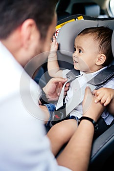 Caucasian father putting smiling baby in child car seat