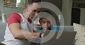 Caucasian father with son sitting in living room and using laptop