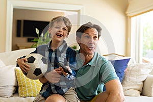 Caucasian father and son watching sports on tv sitting on the couch at home