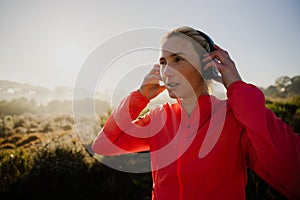 Caucasian female athlete listening to music with headphones while on outdoor run in forest.