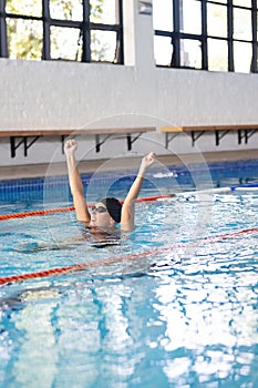 Caucasian female athlete swimmer celebrates in a swimming pool