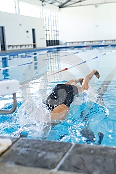 Caucasian female athlete swimmer dives into a swimming pool