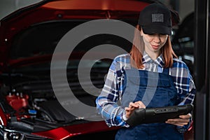 Caucasian female auto mechanic uses a special computer to diagnose faults.