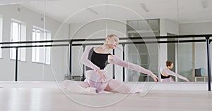 Caucasian female ballet dancer stretching up on the floor and preparing for dance class