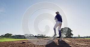 Caucasian female baseball player wearing glasses pitching ball on sunny baseball field