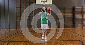 Caucasian female basketball player dribbling and shooting with ball