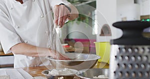 Caucasian female chef adding flour into a bowl