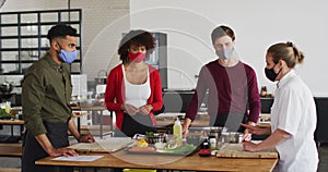 Caucasian female chef teaching diverse group wearing face masks