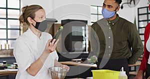 Caucasian female chef teaching diverse group wearing face masks