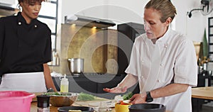 Caucasian female chef teaching diverse group wearing face masks