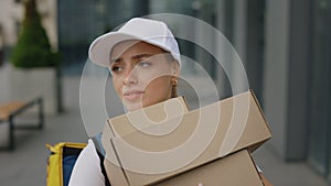 Caucasian Female Courier in White Uniform, Carrying Yellow Backpack, Holding Heavy Packages Carries them in the Business