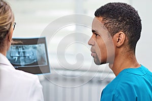 Caucasian female dentist explaining to african male rookie x-ray