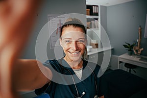 Caucasian female doctor taking selfie in doctors office with cellular device