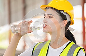 Caucasian female engineer drinking water at the precast factory site, Young forman worker drinking water at construction site photo