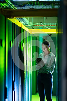 Caucasian female engineer using digital tablet while inspecting in computer server room