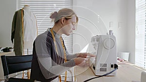 caucasian female fashion designer working from home designing clothing for women using sewing machine