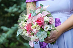 Caucasian female guest or bridesmaid wearing a lilac summer dress which shows a lovely baby bump and holding a wedding bouquet