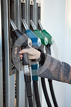 Caucasian female hand holding fueling nozzle with diesel on gas station, close-up view
