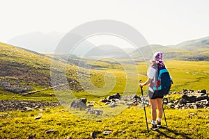 Caucasian female hiker stand enjoy panorama on hilltop on hiking trail outdoors in sunny day on Levanis lake trek in Georgia