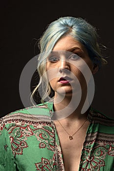 Caucasian female model, Age 22, Blue dyed hair, Red lips, green and red shirt. Isolated on black background. Head and shoulders. H