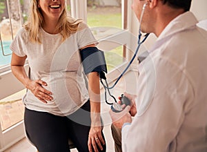 Caucasian female mother to be sitting with doctor measuring blood pressure