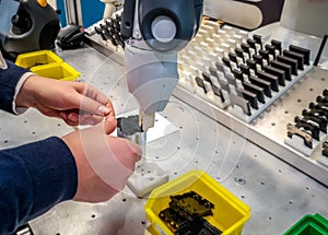 Caucasian female operator standing at an assembly workstation with a collaborative robot or cobot