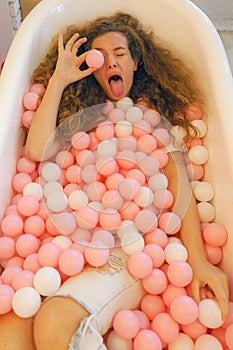 Caucasian female pretty model funny posing in bath tube with color ball