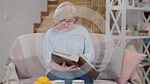 Caucasian female retiree in eyeglasses watching photos closing album sighing sitting in living room at home. Portrait of