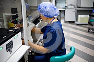 Caucasian Female Scientist Looking Under Microscope, Analyzes Petri Dish Sample. Specialists Working on Medicine, Biotechnology