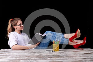 Caucasian female teacher is putting her feet on the table.