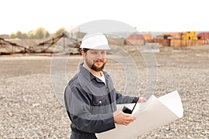 Caucasian foreman holding VHF walkie talkie and papers on construction site.