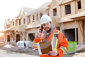 Caucasian foreman talking by smartphone and looking at blueprint.