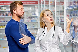 Caucasian friendly pharmacist has a nice conversation with a client, helps to find a medication